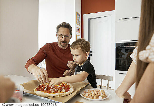 Father and son preparing pizza at home