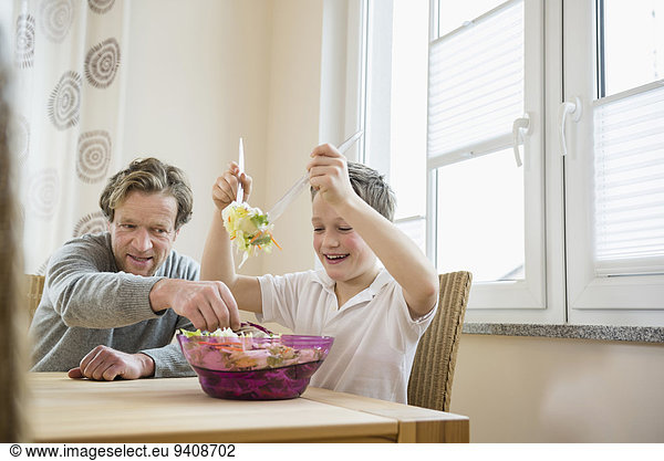 Father and son preparing salad at table