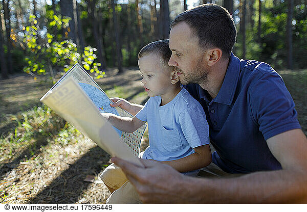 Father and son reading map in forest