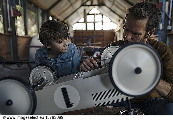 father and son repairing toy car in the barn