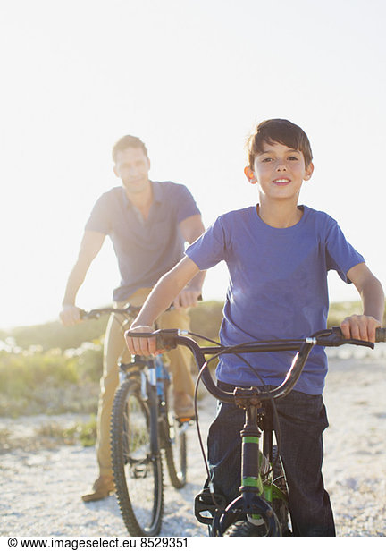 Father and son riding bicycles on sunny beach