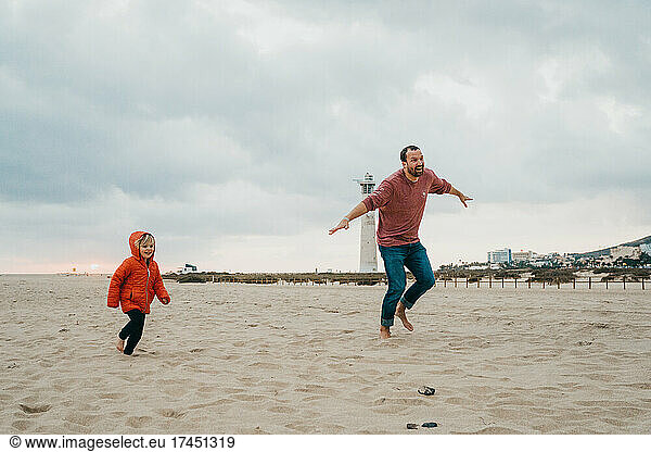 Father and son running in the sand at beach in Canary Islands