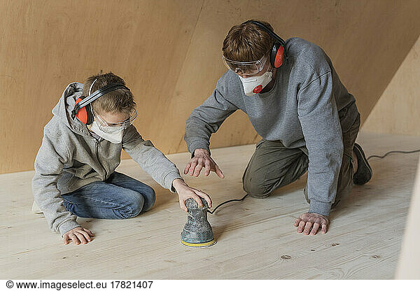 Father and son sanding the floor in their new eco house