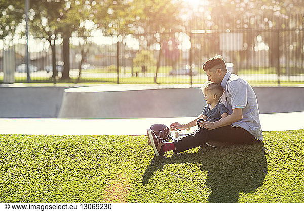 Father and son sitting at grassy field