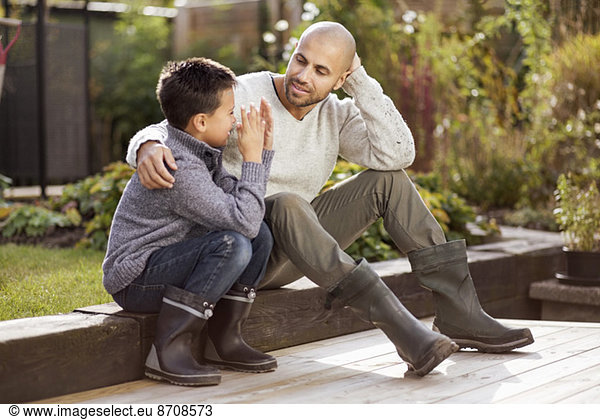 Father and son sitting in garden