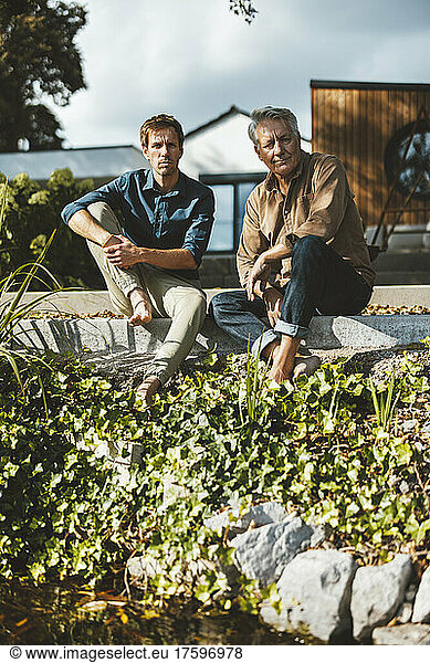 Father and son sitting on steps at backyard