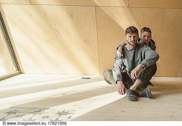 Father and son sitting on the floor in wooden eco house