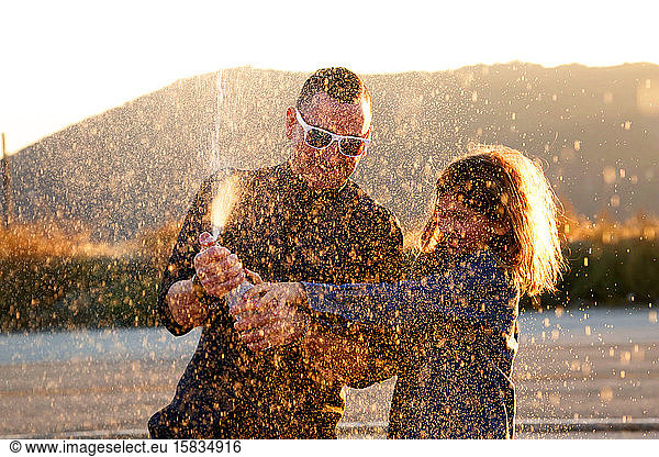 father and son spraying soda in air at sunset