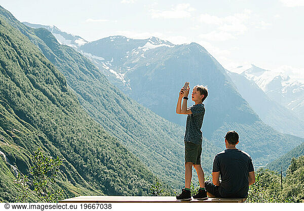 father and son taking pictures of the breathtaking view in Norway