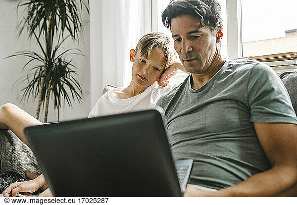 Father and son using laptop at home