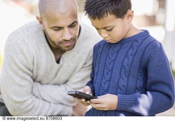 Father and son using mobile phone together