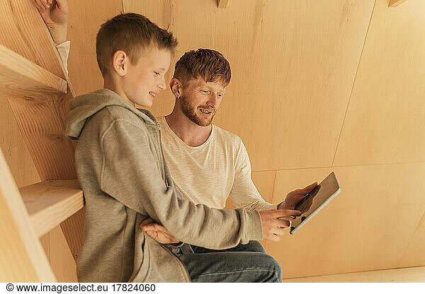 Father and son using tablet pc for creating home interior in eco wooden house