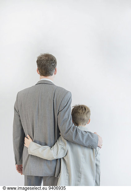 Father and son walking arm in arm against white background