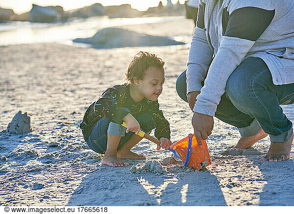 Father and son with Down Syndrome playing in sand on beach