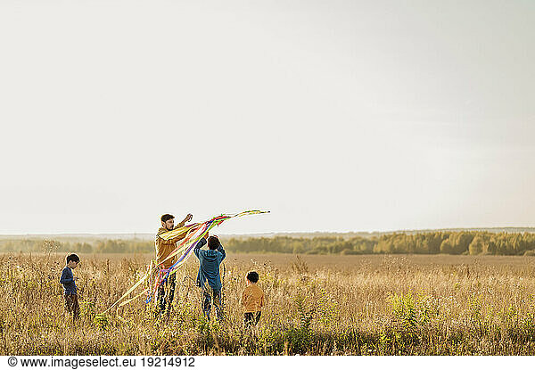 Father and sons holding kite in field