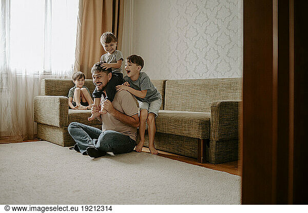 Father and sons spending leisure time on carpet at home