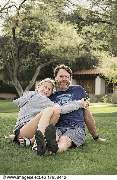 Father and Teenage Girl Embracing on a Grassy Lawn in Arizona