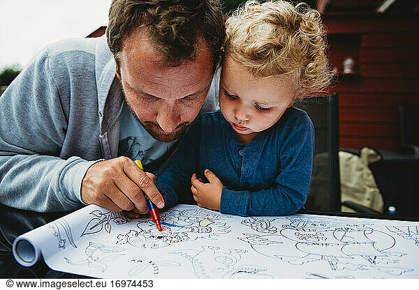Father and young son coloring outside during covid quarantine