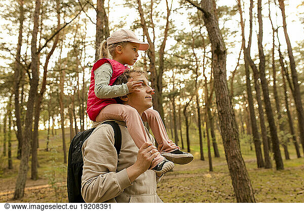 Father carrying daughter on shoulder in forest