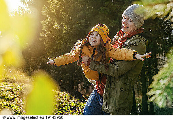 Father carrying playful daughter in forest