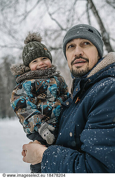 Father carrying son having fun in snow