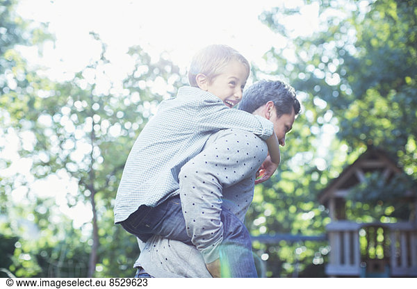 Father carrying son piggyback outdoors