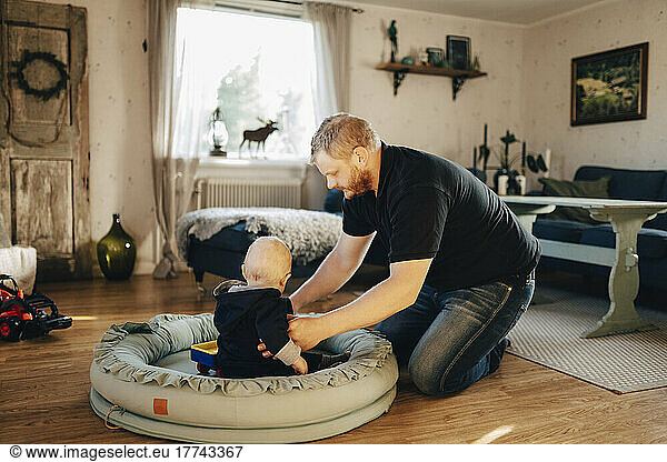 Father carrying son sitting in baby seat at home