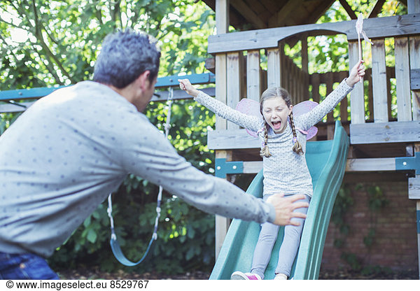 Father catching daughter on slide