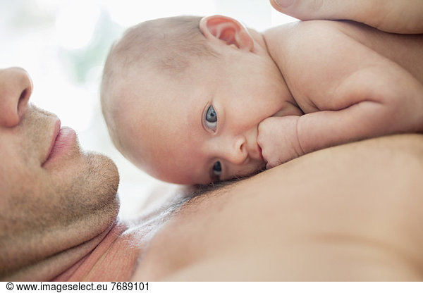 Father cradling newborn baby on chest