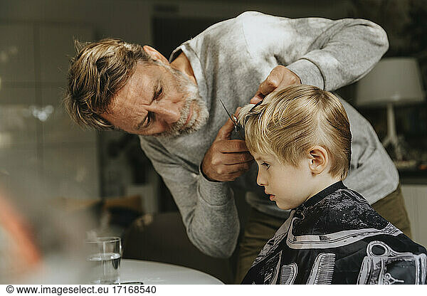 Father doing haircut to son at home