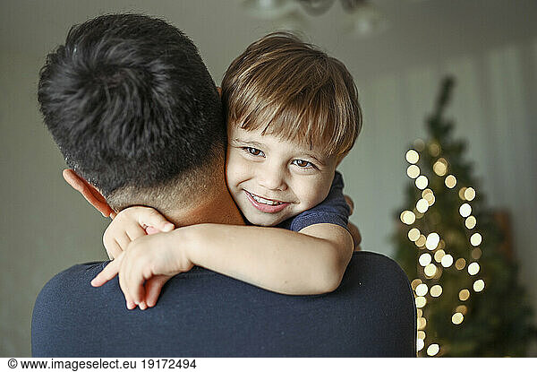 Father embracing smiling son at home