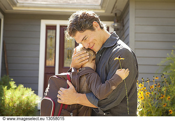 Father embracing son outside house