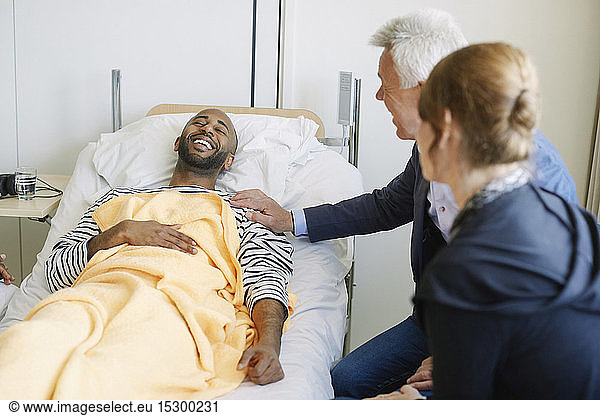 Father encouraging son while sitting by bed at hospital ward
