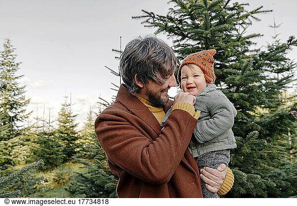 Father enjoying with cute son at Christmas tree farm