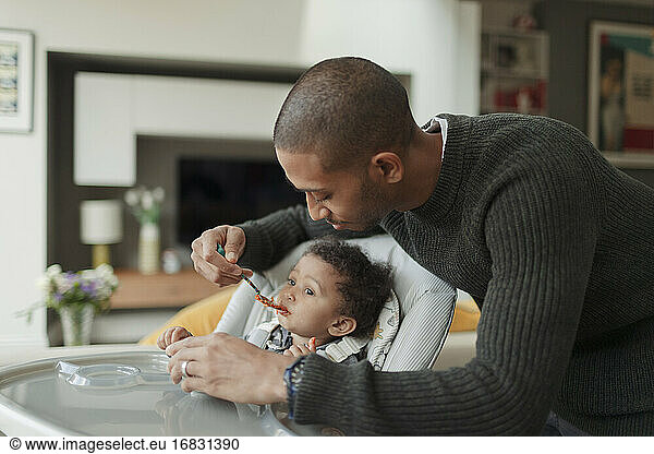 Father feeding baby daughter at high chair