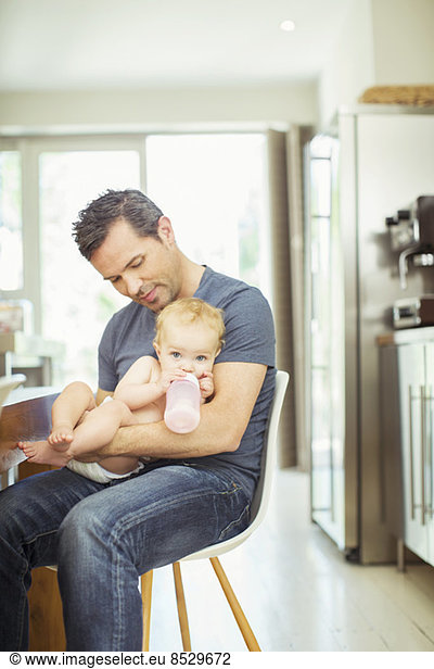 Father feeding baby in kitchen