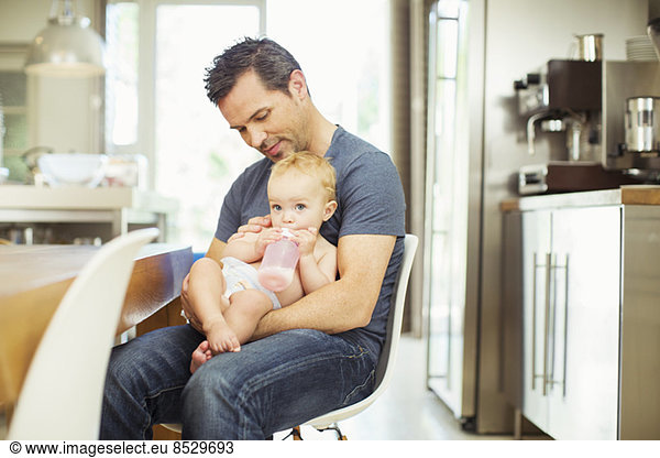 Father feeding baby in kitchen