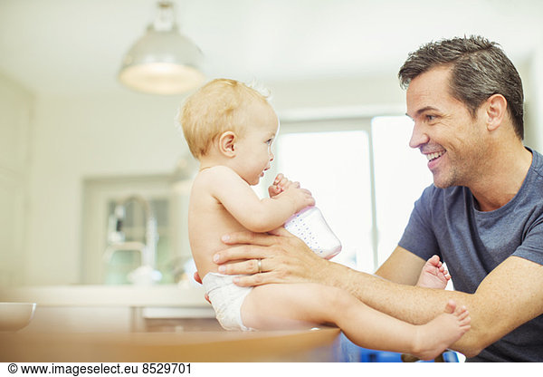 Father feeding baby in kitchen