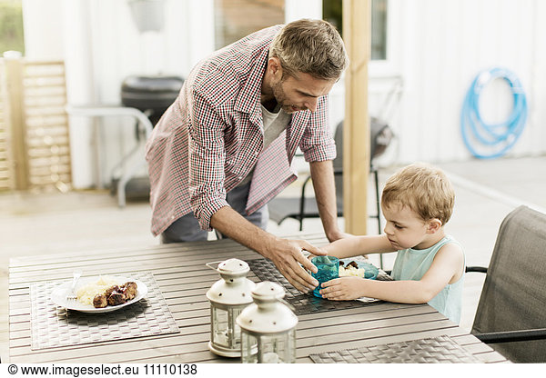 Father feeding son while standing at restaurant