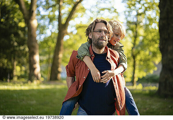 Father giving piggyback ride to son in park