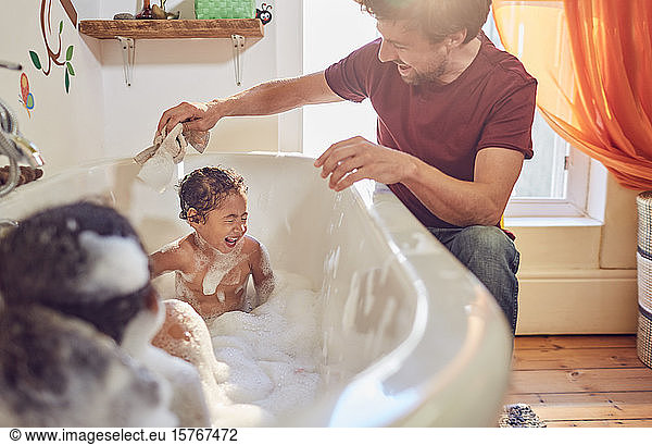 Father giving playful father giving toddler daughters bath
