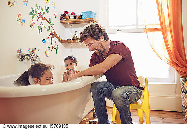 Father giving toddler daughters bubble bath