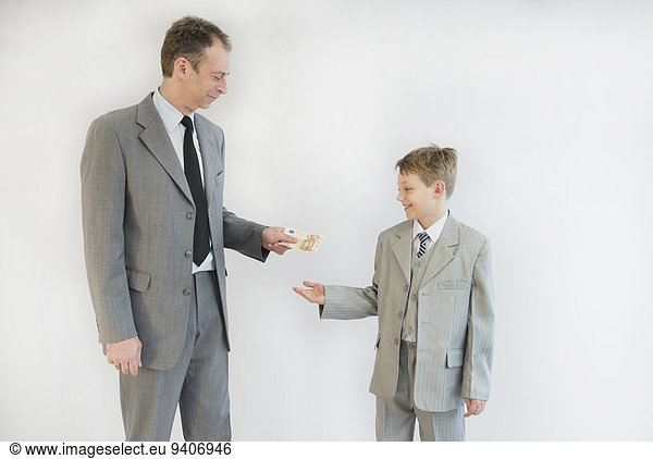 Father handing money to his son  smiling