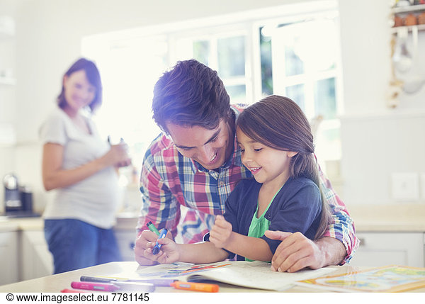 Father helping daughter use coloring book