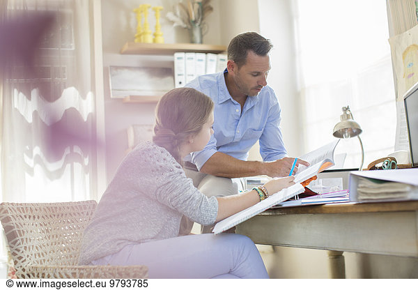 Father helping teenage daughter with her homework