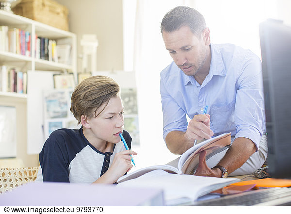 Father helping teenage son with his homework