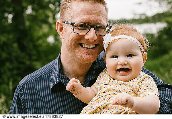 Father hold smiling and happy red haired baby daughter