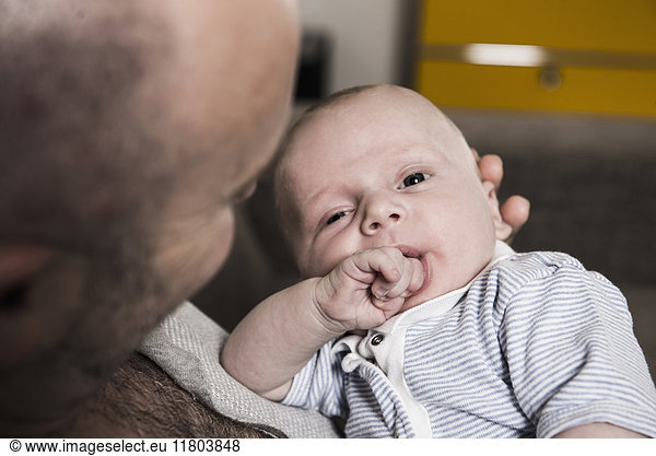Father holding baby boy with finger in mouth