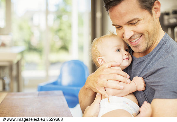 Father holding baby in kitchen