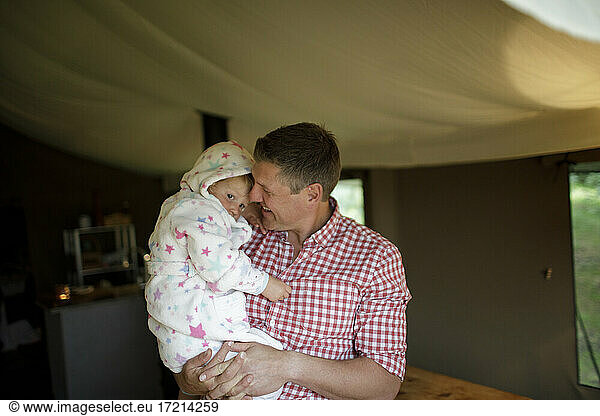 Father holding cute daughter in bathrobe in yurt